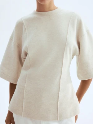 Beige stickad topp med vida ärmar - Säljer en beige stickad topp med rund hals och vida, halvlånga ärmar. Toppen har en avslappnad passform och diskreta sömdetaljer framtill som ger en clean look. Perfekt att styla med jeans eller kjol för en enkel men snygg outfit. Helt ny med prislapp