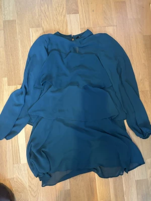 Mörkgrön volangklänning från Zara - Säljer en mörkgrön kortklänning från Zara med långa ärmar och flera lager volanger