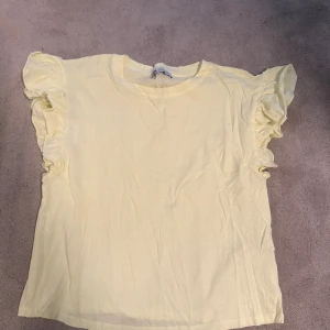 Ljusgul volangtopp från Zara - Supersöt ljusgul topp från Zara med volangdetaljer på ärmarna. Säljer pga att jag nästan aldrig använt den, hör av dig för fler bilder eller frågor!💗