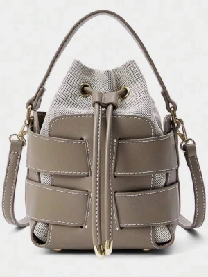 Beige bucket bag med snörning - Säljer en beige bucket bag med cool snörning och gulddetaljer. Väskan har både handtag och axelrem, samt en kombination av slätt skinn och mesh-tyg. Perfekt för dig som vill ha en unik och trendig accessoar till vardagslooken.