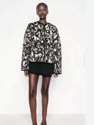 Quiltad svartvit jacka från ZARA - Säljer en quiltad jacka från ZARA med svart och beige leopardmönster. Jackan har rund halsringning, tryckknappar framtill och två fickor. Perfekt för dig som vill sticka ut med ett coolt mönster.