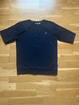 Mörkblå tröja från Napapijri -   12y,152 . Säljer en mörkblå tröja från Napapijri med broderad norsk flagga på bröstet. Tröjan har ribbade muddar vid hals och ärmslut samt kortare ärmar. Tillverkad i mjuk bomull, perfekt för chill vår- och höstdagar.     