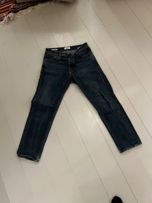 Jack & Jones Relaxed Chris jeans blå 29/30 - Säljer ett par mörkblå jeans från Jack & Jones, modell Relaxed Chris. De har en relaxed fit med raka ben och klassisk femficksdesign. Jeansen är i kraftigt denimtyg med snygga kontrastsömmar och passar perfekt till en chill vardagslook.