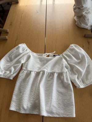 Vit blus med puffärm och knyt i ryggen  - Säljer en superfin vit blus med puffiga trekvartsärmar och knyt i ryggen.