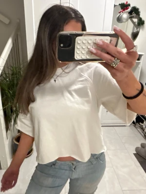 Vit croppad t-shirt - Säljer en vit croppad t-shirt med korta ärmar och avslappnad passform. T-shirten är tillverkad i mjuk bomull och har en enkel, stilren look som passar perfekt till jeans eller shorts.