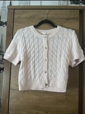 Ljusrosa kabelstickad kofta Gina Tricot - Supersöt ljusrosa kabelstickad kofta från Gina Tricot med korta ärmar och snygga guldfärgade knappar framtill. Storlek 158/164 men passar mig som har xs/s