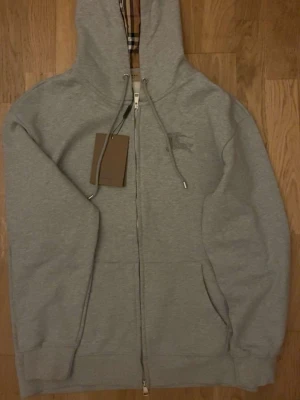Grå hoddie fårn Burberry med en hel dragkedja  - Grå burberry hoddie, helt ny oanvänd och priset kan diskuteras!!!