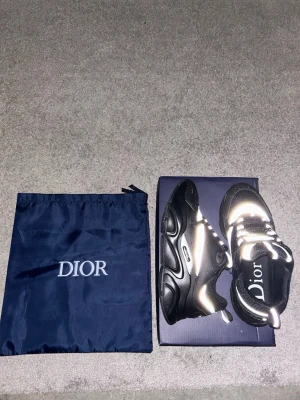 Dior sneakers svart/silver strl 41 - Säljer ett par feta Dior sneakers i svart och silver med chunky sula och reflekterande detaljer. Skorna har snörning och är tillverkade i en mix av mesh och skinn för en lyxig vibe. Kommer med originalpåse och box. Perfekta för dig som vill sticka ut.