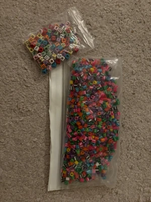 1 påse med randiga färgade pärlor och 1 påse med färgade bokstavspärlor - 2st påsar med olika pärlor, 1 med färgade randiga pärlor och 1 med färgade bokstavspärlor, skicka för fler bilder. Finns att köpa i bundle med annat.