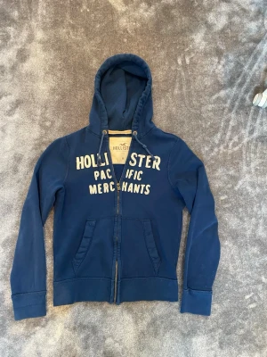 Hollister hoodie (oerhört eftertraktad) - Tjena! Säljer nu denna oerhört snygga zip-hoodien från Hollister. Storleken är M och passformen är Slim/regular. Säljs då den har blivit lite liten på mig. Denna tröja är extremt eftertraktad och ovanlig! Skicket är enligt mig mycket bra men använt skick! Vid fler frågor är det bara att höra av er!