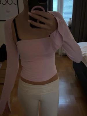 Ljusrosa offshoulder topp - ljusrosa offshoulder topp med lång ärm och tight passform. Toppen har en rak skärning över bröstet och är croppad.