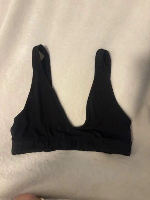 Svart bambu-bh från 157 - En enkel och mjuk svart bh från 157 i bambumaterial. Modellen har breda axelband och djup v-ringning framtill, perfekt för en chill och bekväm stil. Sitter skönt med resår under bysten.