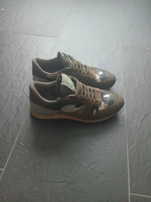 Valentino Rockrunner sneakers camo - Säljer ett par Valentino Rockrunner sneakers med snyggt camouflage-mönster i grönt, brunt och beige. Skorna har rund tå, snörning och detaljer i mocka och skinn. Storlek 40 men passar även 41. Lite skrap märker där framme (kolla bild 3) men inte man tänker på. 