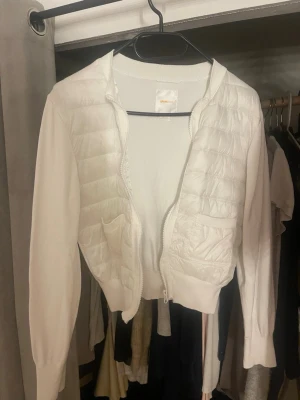 Vit quiltad pufferjacka från Gina Tricot - Säljer en vit pufferjacka från Gina Tricot med quiltade partier framtill och två små fickor. Jackan har dragkedja, ribbade muddar och lång ärm. Perfekt för dig som vill ha en clean och stilren look.