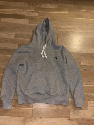 Polo Ralph Lauren hoddie grå - Bekväm och stilig grå hoddie från Ralph lauren. Perfekt för skolan och hemma. Passar bra nu till vintern när det är kallt då ett varmt och stiligt plagg behövs. Passar S men också XS. Tröjan är använd ett fåtal gånger och säljer eftersom den är för liten. Pris kan diskuteras !