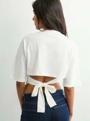 Nelly tröja med rosett i ryggen - Säljer en vit croppad topp med korta ärmar och snygg knytning i ryggen. Använd fåtal gånger 