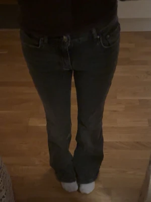 Mörkgråa bootcut jeans  - Säljer ett par mörk gråa jeans med bootcut-modell. Jeansen har klassisk femficksdesign och normal passform. Lite slitna nere vid fötterna.