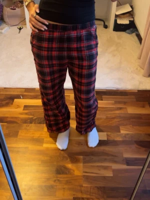 Rutig röd och svart byxa från H&M❤️ - Säljer ett par sköna byxor från H&M i rött och svart rutigt mönster. Byxorna har resår i midjan och raka ben, perfekta för chill dagar hemma. Tillverkade i bomull.