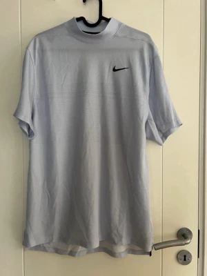 Nike Tiger Woods Dri-FIT ADV t-shirt - Snygg ljusgrå t-shirt från Nike Tiger Woods Collection med svart swoosh-logga på bröstet och TW-logga i nacken. Tillverkad i tekniskt Dri-FIT ADV-material som andas och håller dig torr. Klassisk passform med korta ärmar och rund hals.