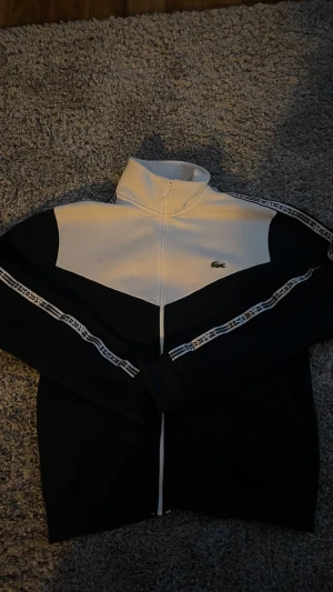 Lacoste tröja - Snygg tröja från Lacoste i blått och vitt. Storlek M kan även passa S. Det är en ganska skön tröja den är perfekt nu till vintern. Hör av er vid fler frågor 