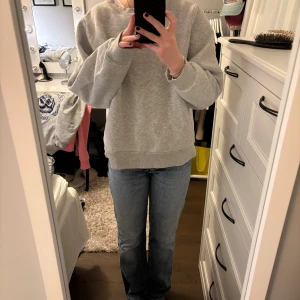 Blå raka jeans från Zara, strl 34 - Säljer ett par klassiska blå jeans från Zara i storlek 34. Modellen har rak passform, låg midja och fem fickor. Jeansen är tillverkade i jeansmaterial med snygga kontrastsömmar och knappstängning framtill. Perfekt för en chill och stilren look.