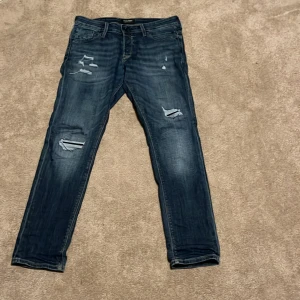 Blå slitna jeans från jack n jones - Snygga jeans från jack&jones med slitningar på framsidan och lite lite på baksidan rätt så nya och storlek 31/30