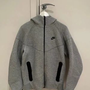 Nike tech fleece - En grå Nike tech hoodie som är knappt andvänt väldigt bra skick säljer den pga den är för liten för mig, alla är bra med den bara en lilla den har ett litet fläck vid dragkedjan som man knapp märker. Pris kan diskuteras vid snabb äffar! 
