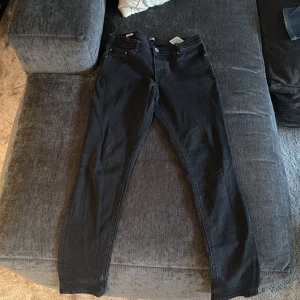 Svarta skinny jeans från Jack & Jones - Snygga svarta jeans från Jack & Jones i skinny fit. Klassisk femficksmodell med knapp och dragkedja fram. Jeansen är tillverkade i mjukt denimtyg med stretch för extra komfort. Passar dig som gillar en smal siluett och stilren look.