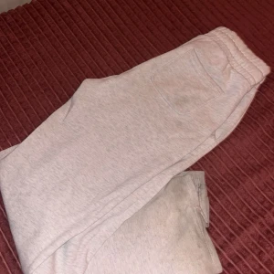 Ljusgrå mjukisbyxor med snörning - Säljer ett par ljusgrå mjukisbyxor med elastisk midja och snörning. Byxorna har fickor på sidorna och en bakficka. Perfekta för chill dagar eller när du vill vara extra bekväm. Tillverkade i mjukt bomullsmaterial.