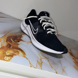 Svarta Nike sneakers med vit sula - Snygga svarta Nike sneakers med vit sula och vit swoosh på sidan. Skorna har rund tå, snörning och är tillverkade i mesh och syntetmaterial för bra andningsförmåga. Perfekta för träning eller chill. Klassisk design med kontrasterande detaljer.Inte använda så mycket 2-5