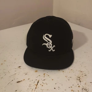 Svart White Sox keps från New Era - Snygg svart keps från New Era med Chicago White Sox-logga broderad i vitt framtill. Klassisk 59FIFTY-modell med rak skärm och MLB-logga baktill. Kepsen är tillverkad i 100% polyester och har New Era-logga på sidan.