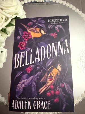 Belladonna - En mystisk och vackert illustrerad bok med mörka blommor och fåglar på omslaget. Perfekt för dig som gillar spänning och dramatik, och vill ha något som sticker ut i bokhyllan. Skriven av en New York Times-bestsäljande författare.