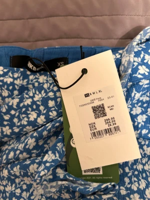 Blå blommig kjol från Bikbok - Supersöt blå kjol från Bikbok med vitt blommönster och smala axelband. Kjol har omlottmodell med knyt i sidan. Aldrig använd, pris kan diskuteras