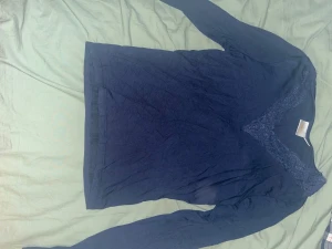 Mörkblå långärmad topp Gina Tricot - Snygg mörkblå långärmad topp från Gina Tricot med v-ringad hals och dekorativ spetskant. Perfekt för dig som gillar stilrena detaljer och vill ha en bekväm men ändå trendig look. Materialet är mjukt och stretchigt, vilket gör den skön att bära hela dagen.