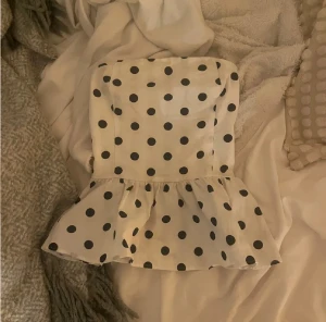 Vit prickig tubtopp - Supersöt vit bandeau tubtopp med svarta prickar och volang nertill. Toppen är i ny skick!! 