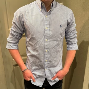 Randig Ralph Lauren skjorta - Super snygg skjorta från Ralph lauren. Nyskick iprincip aldrig använd och har inga defekter. Min lillebror säljer eftersom han inte använder den! Han är 180 lång och denna sitter bra på han :)