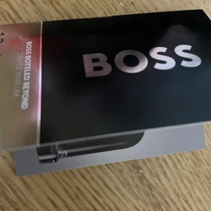 Boss Bottled Beyond EdP Sample - Upptäck Boss Bottled Beyond Eau de Parfum – en fräsch, träig och läderaktig doft med eterisk olja av cederblad, ingefärsextrakt, saffran och läder. Perfekt för dig som vill sticka ut med stil.