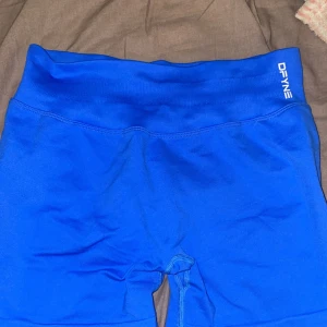Blå träningstights-shorts från DFYNE - Säljer ett par blå seamless träningstights-shorts från DFYNE i storlek medium. De är högmidjade med bred resår och har en tight passform som framhäver formerna. Materialet är stretchigt och består av 90% nylon och 10% elastan. Perfekta för gymmet eller löpning.