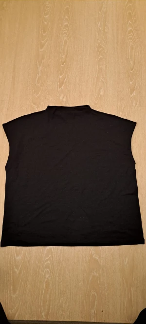 Svart ärmlös topp från Lindex XXL - En stilren svart ärmlös topp från Lindex i storlek XXL. Toppen har en enkel och rak passform med hög halsringning och är tillverkad i mjuk bomull. Perfekt att matcha med jeans eller kjol för en clean look.