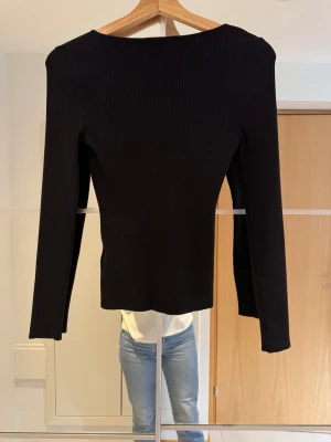 Svart ribbad tröja - Svart långärmad ribbstickad topp med hjärtformad urringning,, i mjukt material. Storlek XS-S. 