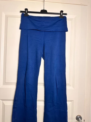 Blå vida byxor från Pull&Bear - Snygga blå byxor från Pull&Bear i storlek L. Modellen har bred linning som kan vikas ner och vida ben för en chill vibe. Materialet är mjukt och stretchigt, perfekt för en avslappnad look. Passar dig som gillar bekväma och trendiga plagg.