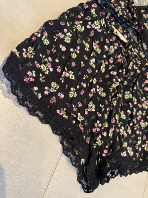 Blommiga spetsshorts - Blommiga shorts med spets och snörning. Matchande topp/toppar säjs i separat annons. Storlek XS-S. Svart, rosa, grön. 