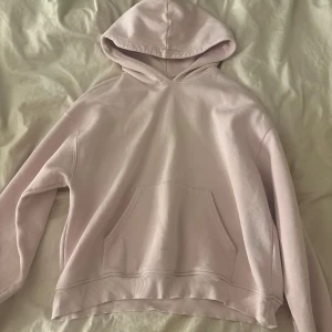 Ljusrosa hoodie - Säljer en ljusrosa hoodie med stor huva och magficka. Tröjan har långa ärmar och ribbade muddar vid ärmslut och nederkant. Perfekt för chill dagar och enkel att matcha med jeans eller mjukisbyxor.