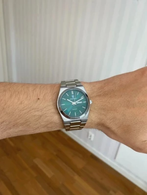 Poedagar Herrklocka Quartz 41mm rostfritt stål - Stilren klocka från Poedagar med grön urtavla och dag/datumvisning. Armbandet är i silverfärgat rostfritt stål med klassisk länkdesign. Quartz-urverk och rund boett i metall. Perfekt accessoar för dig som gillar modern och clean stil.