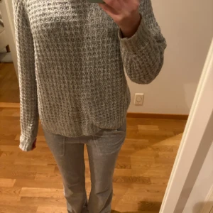 Grå stickad tröja från 157 XS - Mysig grå stickad tröja från 157 i storlek XS. Tröjan har ett grovt, ribbat mönster och långärmade ärmar. Perfekt för dig som gillar en enkel och chill stil med lite struktur i materialet. Passar dig som vill ha en basic men ändå snygg tröja.