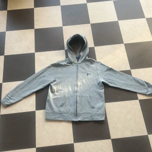 Grå hoodie från Polo Ralph Lauren S - Snygg grå hoodie från Polo Ralph Lauren i storlek S. Tröjan har huva, dragkedja framtill och två stora fickor. Materialet är mjukt och skönt, perfekt för chill dagar. Klassisk logga på bröstet och ribbade muddar vid ärmslut och nederkant. 18-20 år XL men passar S