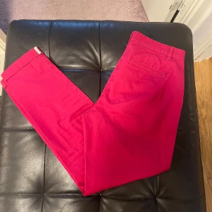 Rosa chinos med rak passform - Snygga rosa chinos med klassisk rak passform och midwaist. Byxorna har sidofickor, bakficka med diskret söm och hällor för bälte. Tillverkade i mjuk bomull som är skön mot huden. Perfekt för dig som vill sticka ut med färg.helt ny,bara tvättad