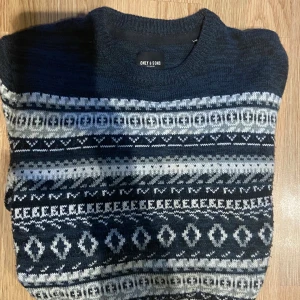 Mönstrad stickad tröja - Säljer en mörkblå stickad tröja från Only & Sons med snyggt geometriskt mönster i vitt och grått. Mysig och skön på vintern eller kallare dagar