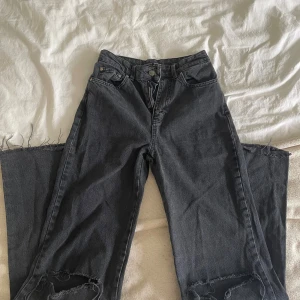 Svarta straight fit jeans Stradivarius - Säljer ett par svarta jeans från Stradivarius i modellen long straight fit. Jeansen har råa, fransiga benslut och slitningar vid knäna för en cool look. Klassisk femficksmodell med hög midja och dragkedja. Perfekta till sneakers eller boots.