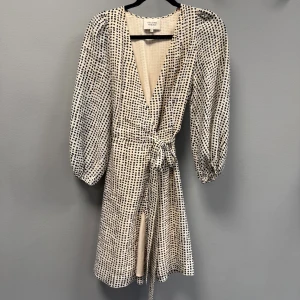 Prickig omlottklänning Second Female - En super snygg kort omlottklänning från Second Female i beige med svarta prickar. Passat perfekt till alla tillfällen!!💗(nypris 2000)